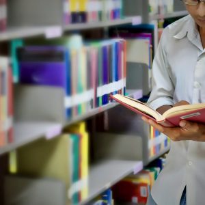 man with book in front of bookshelves