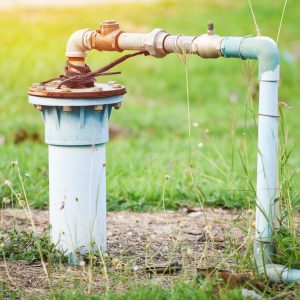 Groundwater well with pvc pipe and system electric deep well submersible pump water on green meadow / groundwater testing and sampling pollution concept