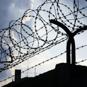 Dramatic clouds behind barbed wire fence on a prison wall